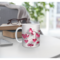 3D hearts effect ceramic coffee cup. Custom name pink hearts drinkware. Personalized heart-themed mug on a table with books. 